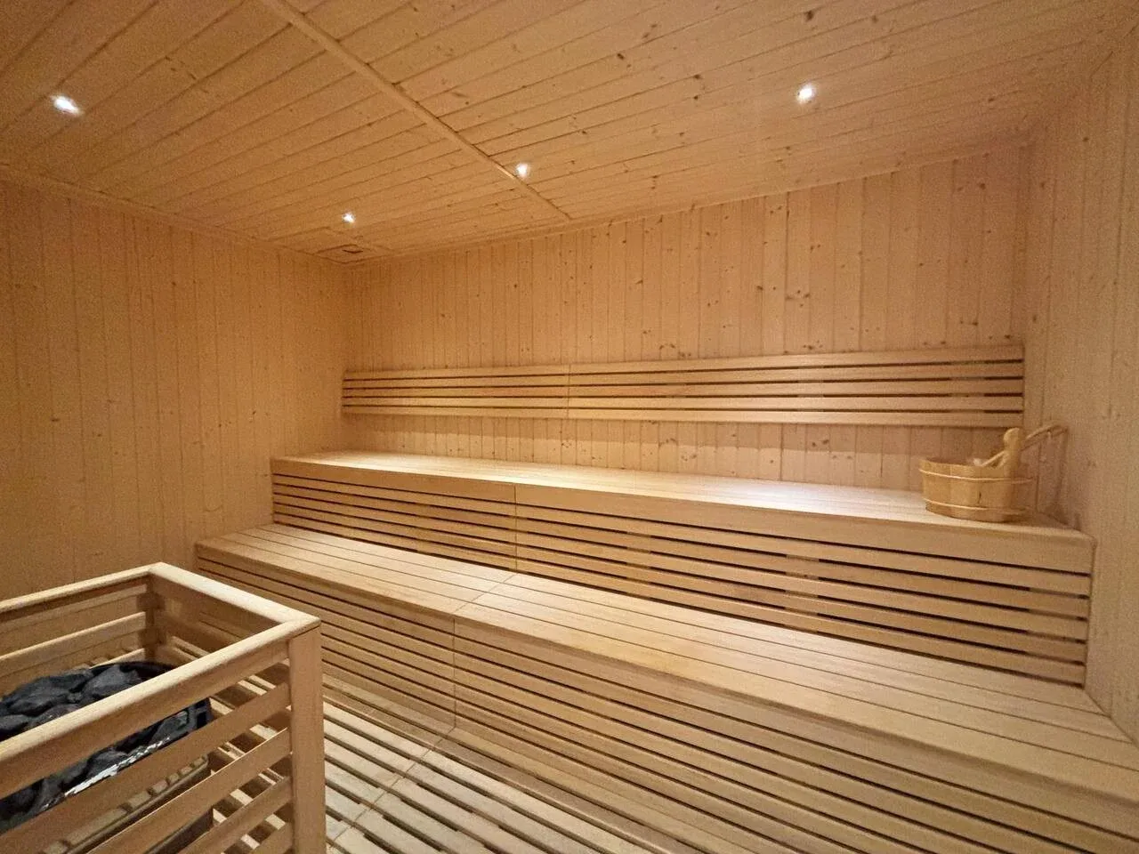 Una sauna revestida de madera con asientos escalonados y un calentador.