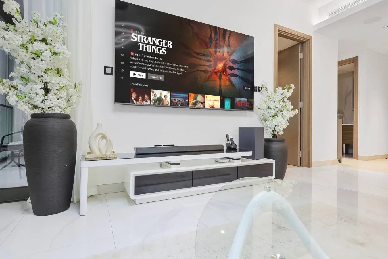 Una sala luminosa con un televisor montado en la pared sobre un mueble bajo.