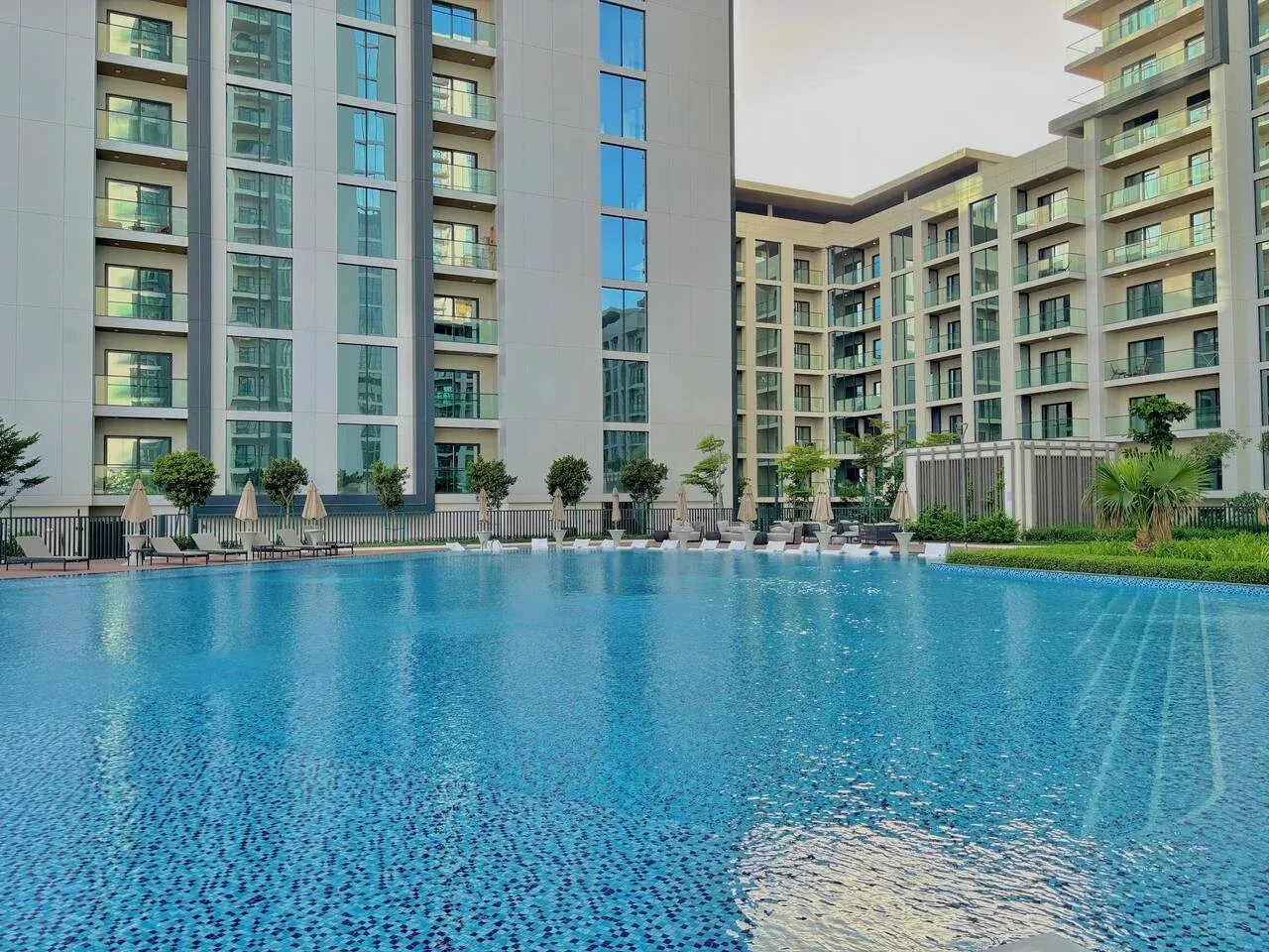 Una piscina está frente a un edificio moderno de varios pisos.