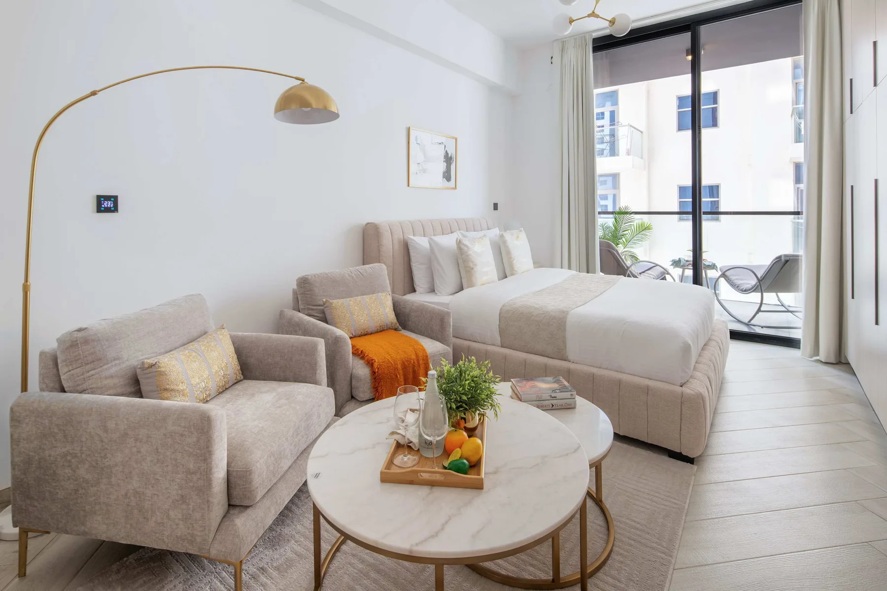 A bright bedroom with a bed, seating, and a round coffee table by the balcony doors.