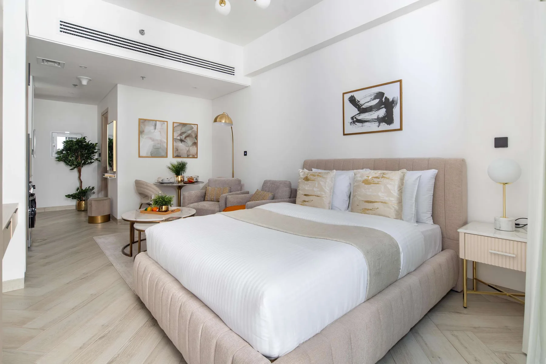 A bright bedroom features a large bed and a small seating area.