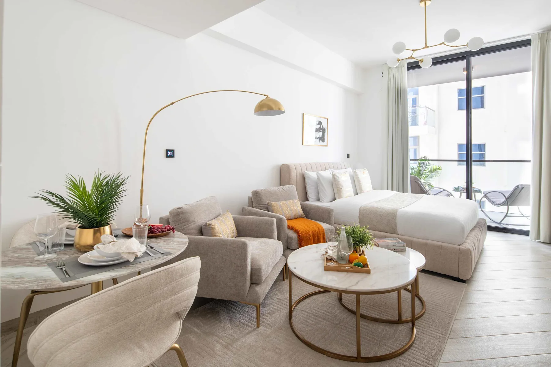 A bright living room with a seating area beside a bed and large windows.