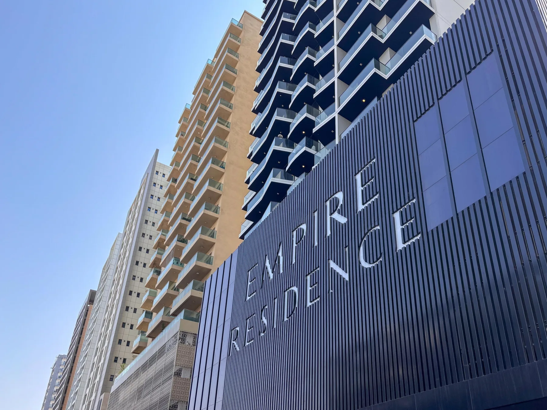 A modern high-rise building rises above a dark facade with large lettering.