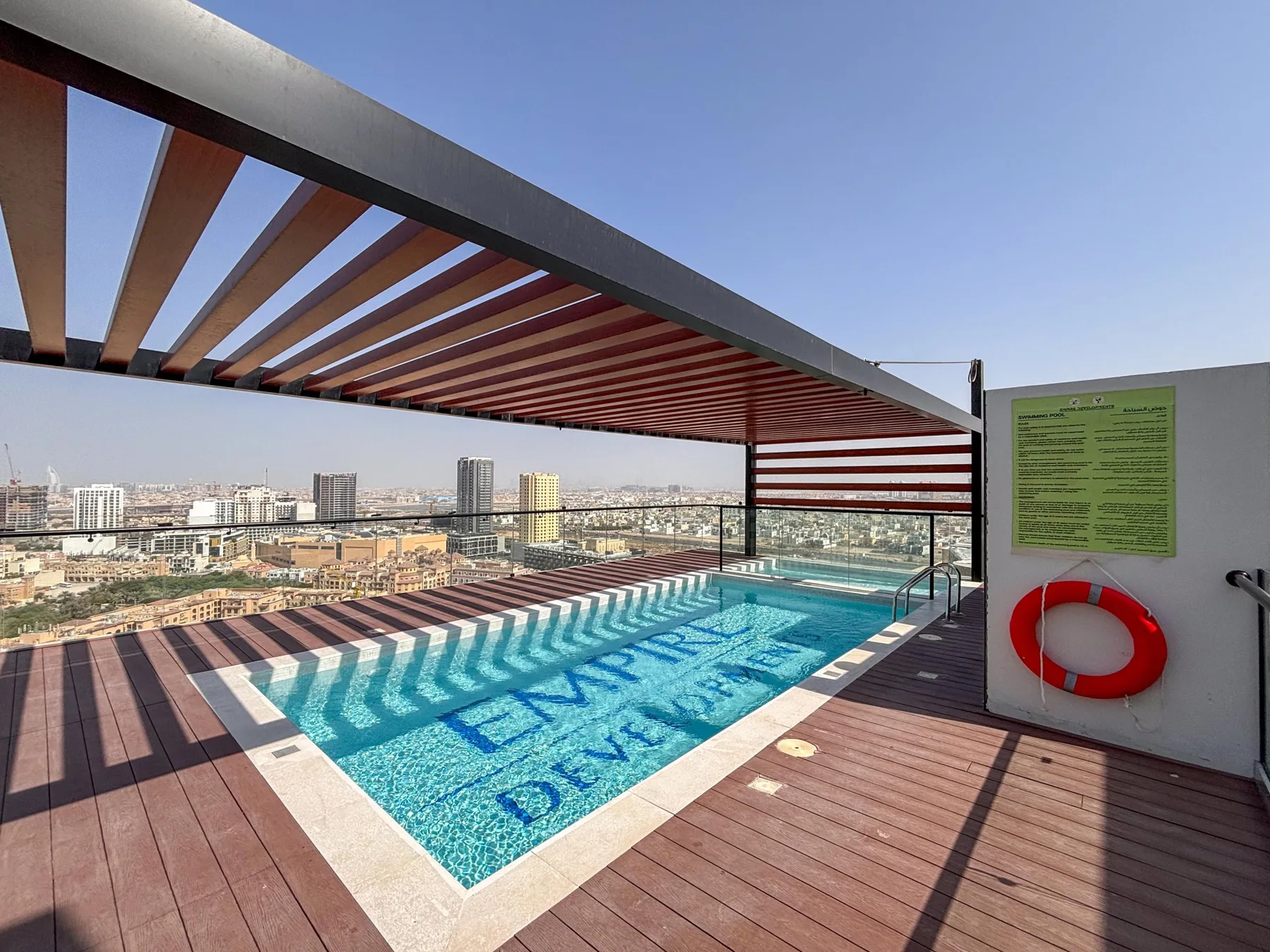 A rooftop pool beneath a slatted canopy overlooks the city.