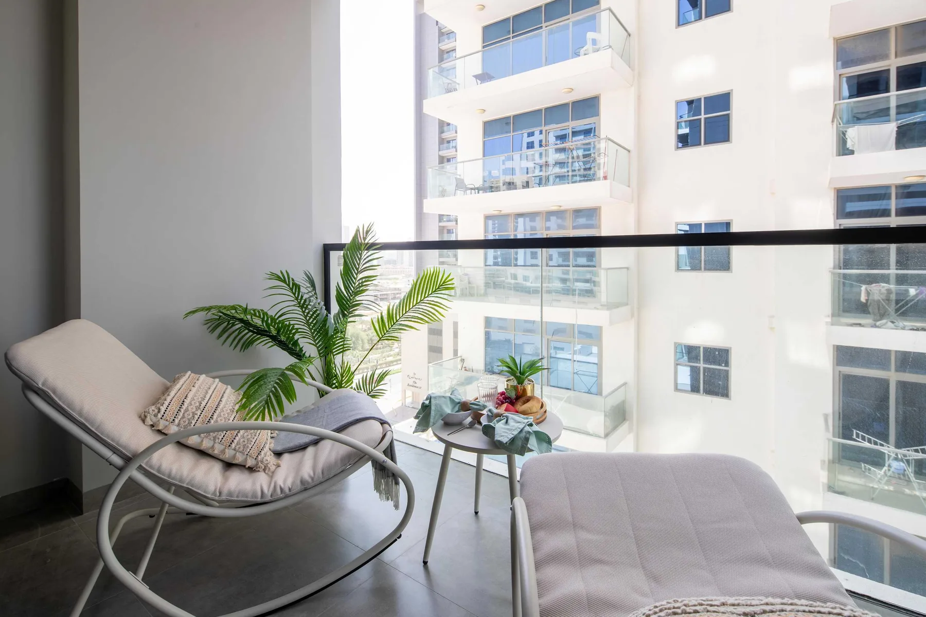 A balcony seating area with a cushioned chair, small table, and potted plants.