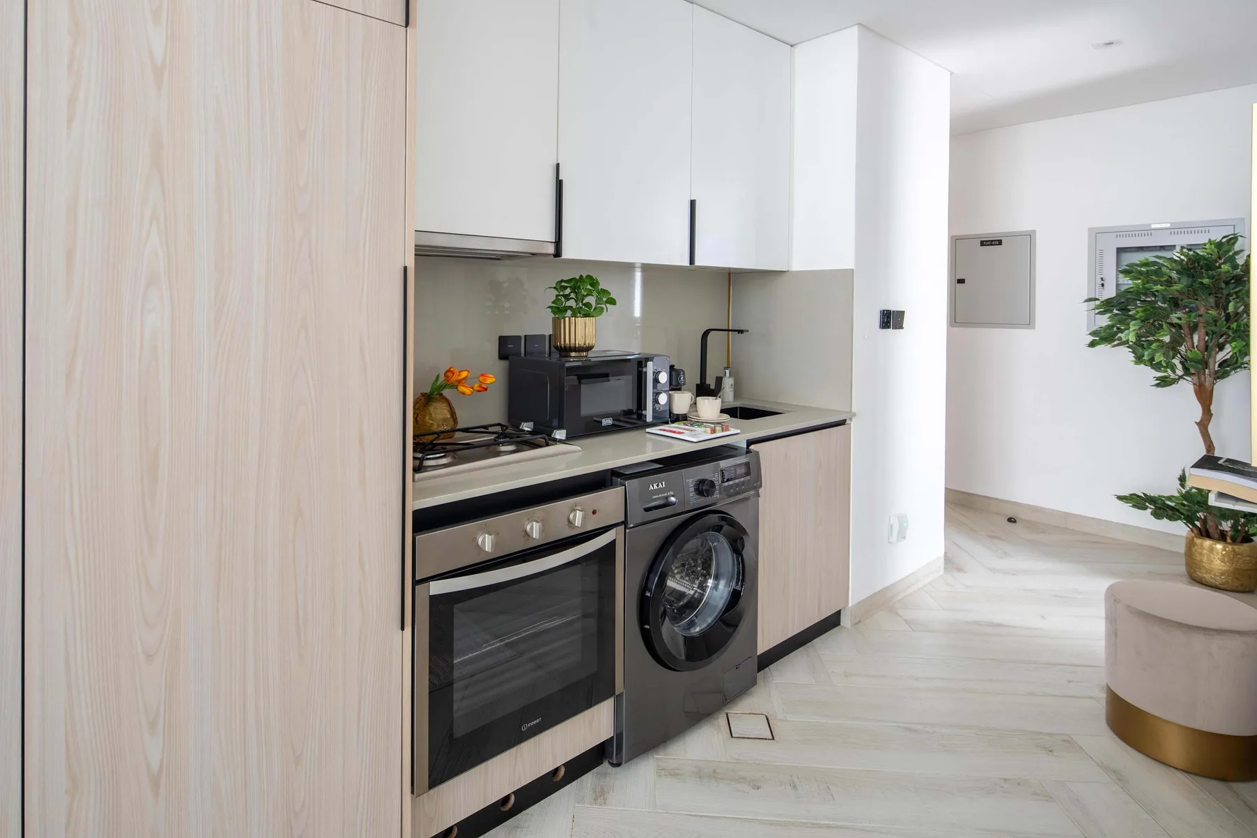 A modern kitchen with white cabinetry, a cooktop, and a washing machine.