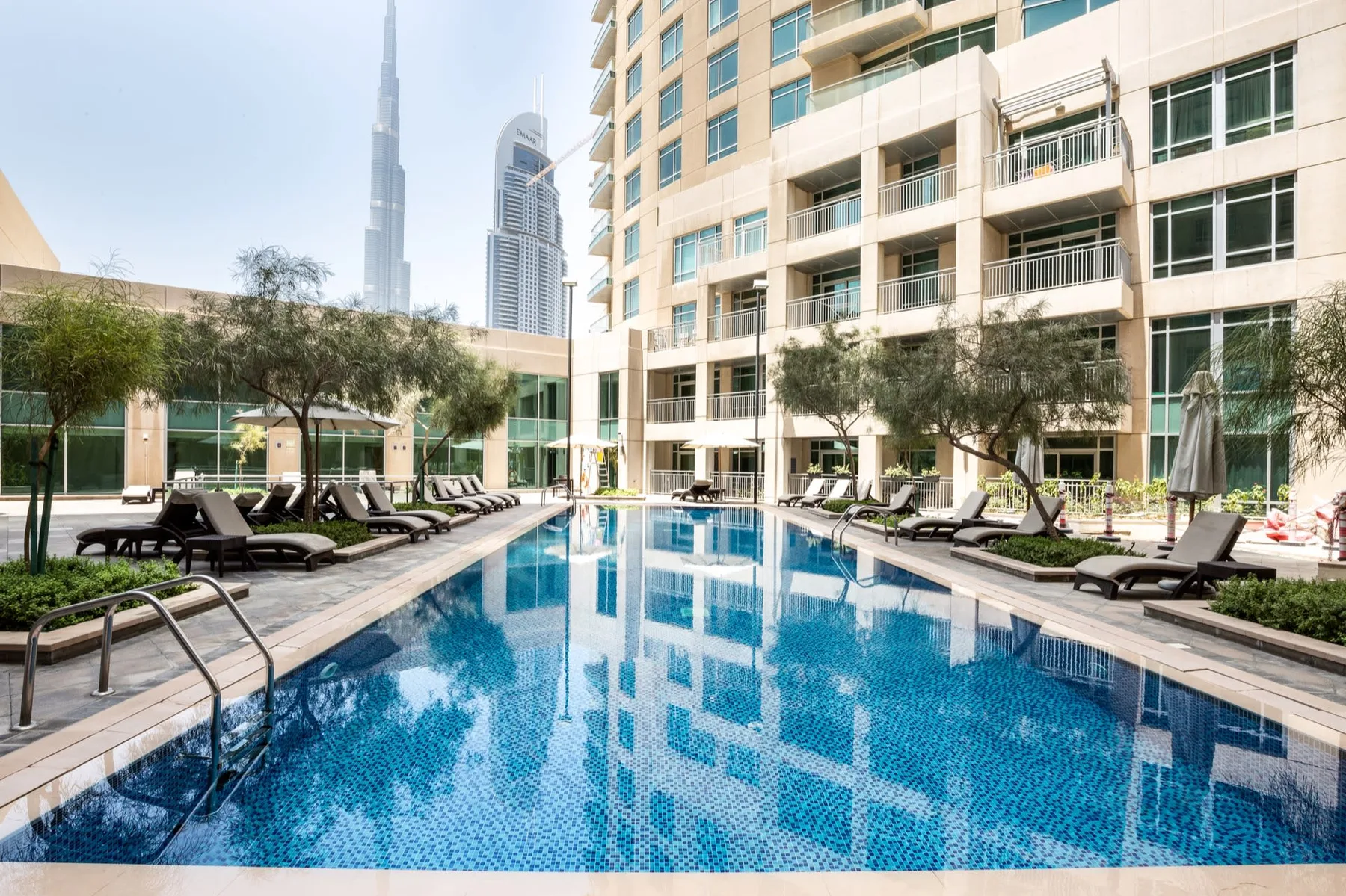 Una piscina al aire libre está rodeada de asientos junto a un edificio moderno.