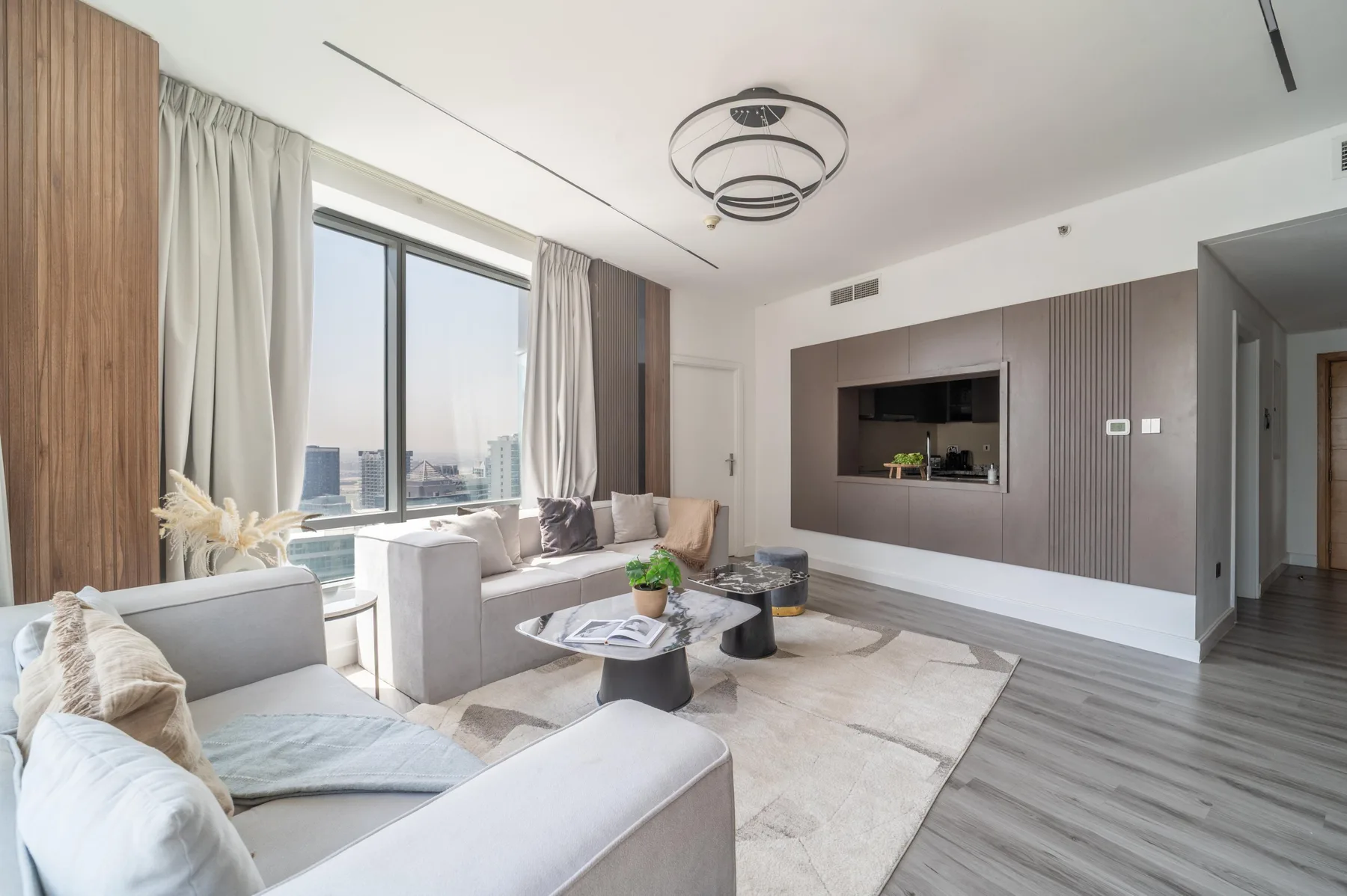 Una sala luminosa con asientos junto a grandes ventanales y una mesa de centro baja.