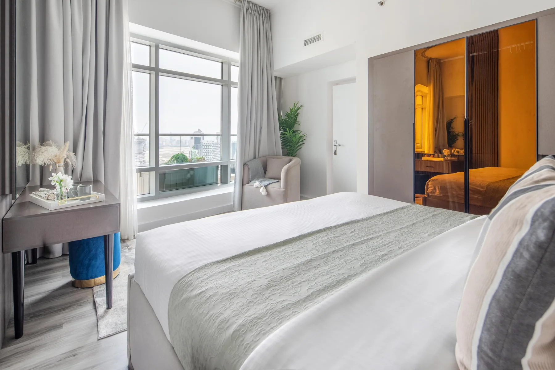 Un dormitorio luminoso con una cama grande junto a una ventana amplia.