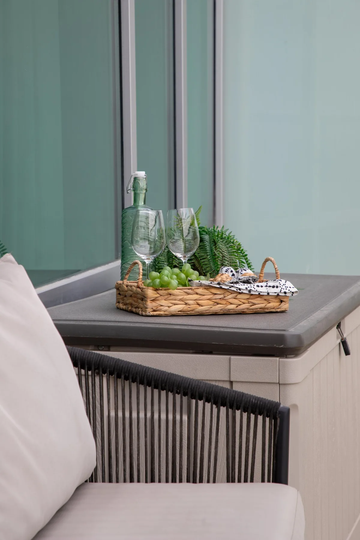 Una zona de estar en el patio con un asiento acolchado y una bandeja de bebidas sobre una mesa.