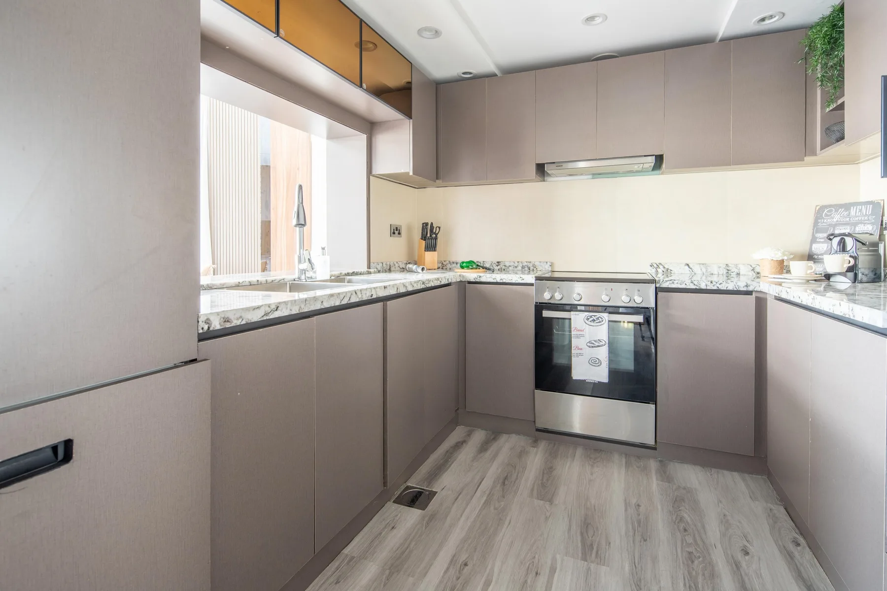 Una cocina moderna con encimeras en forma de L y un horno integrado.