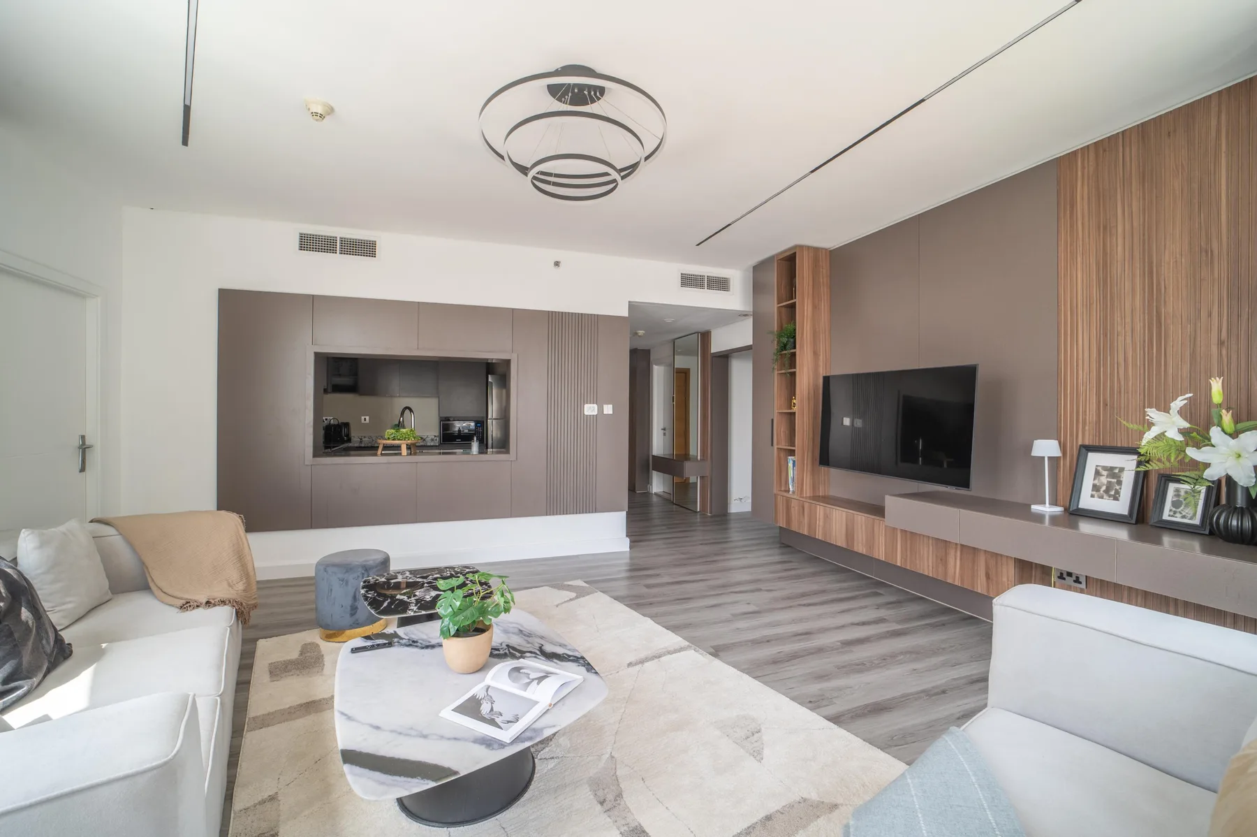Una sala de estar moderna con asientos, un televisor y una cocina abierta.