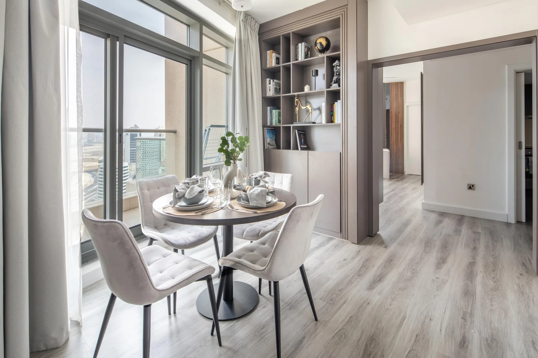 Un comedor luminoso con una mesa redonda y sillas junto a grandes ventanas.