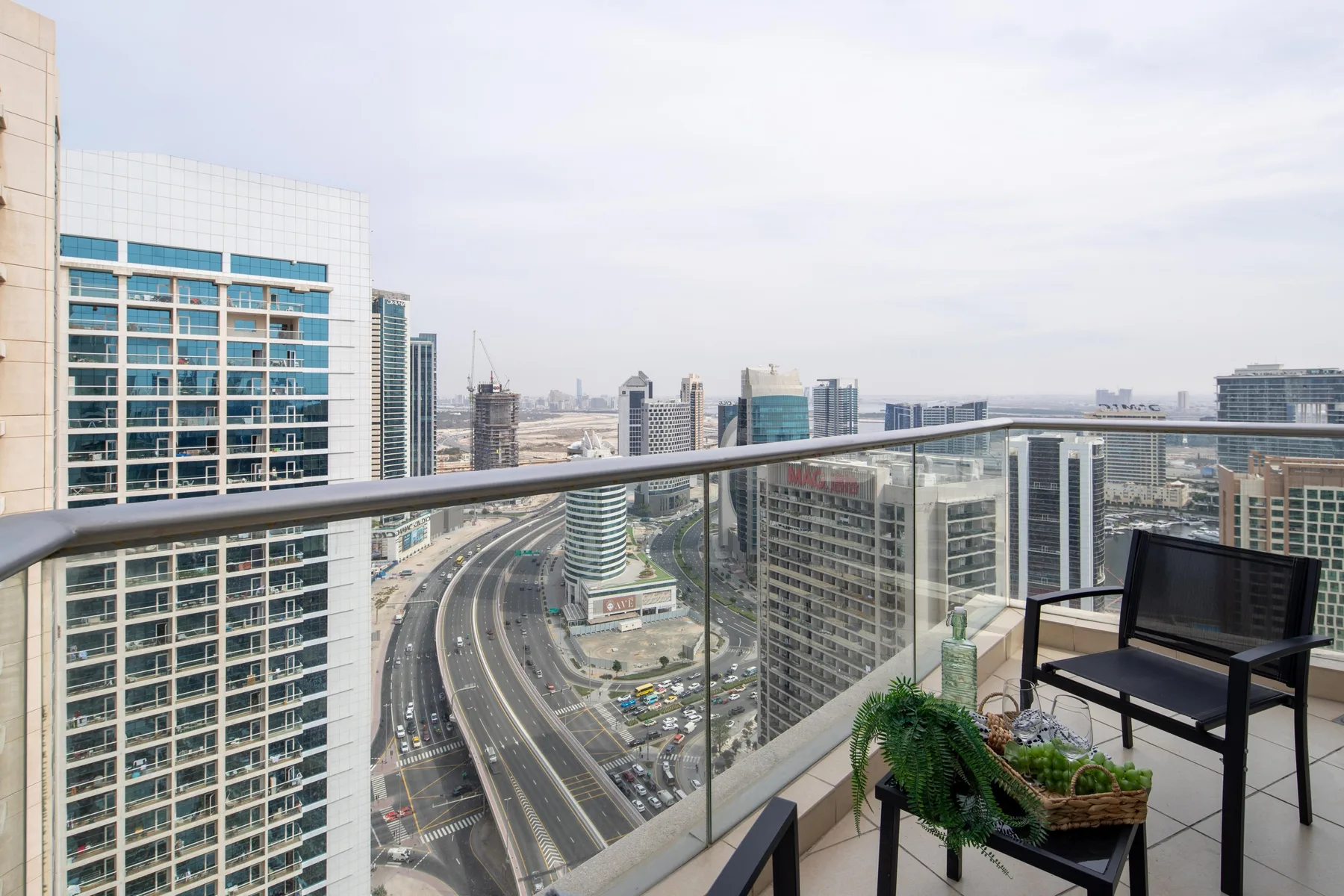 Un balcón con asientos ofrece vistas del horizonte urbano y vías elevadas.