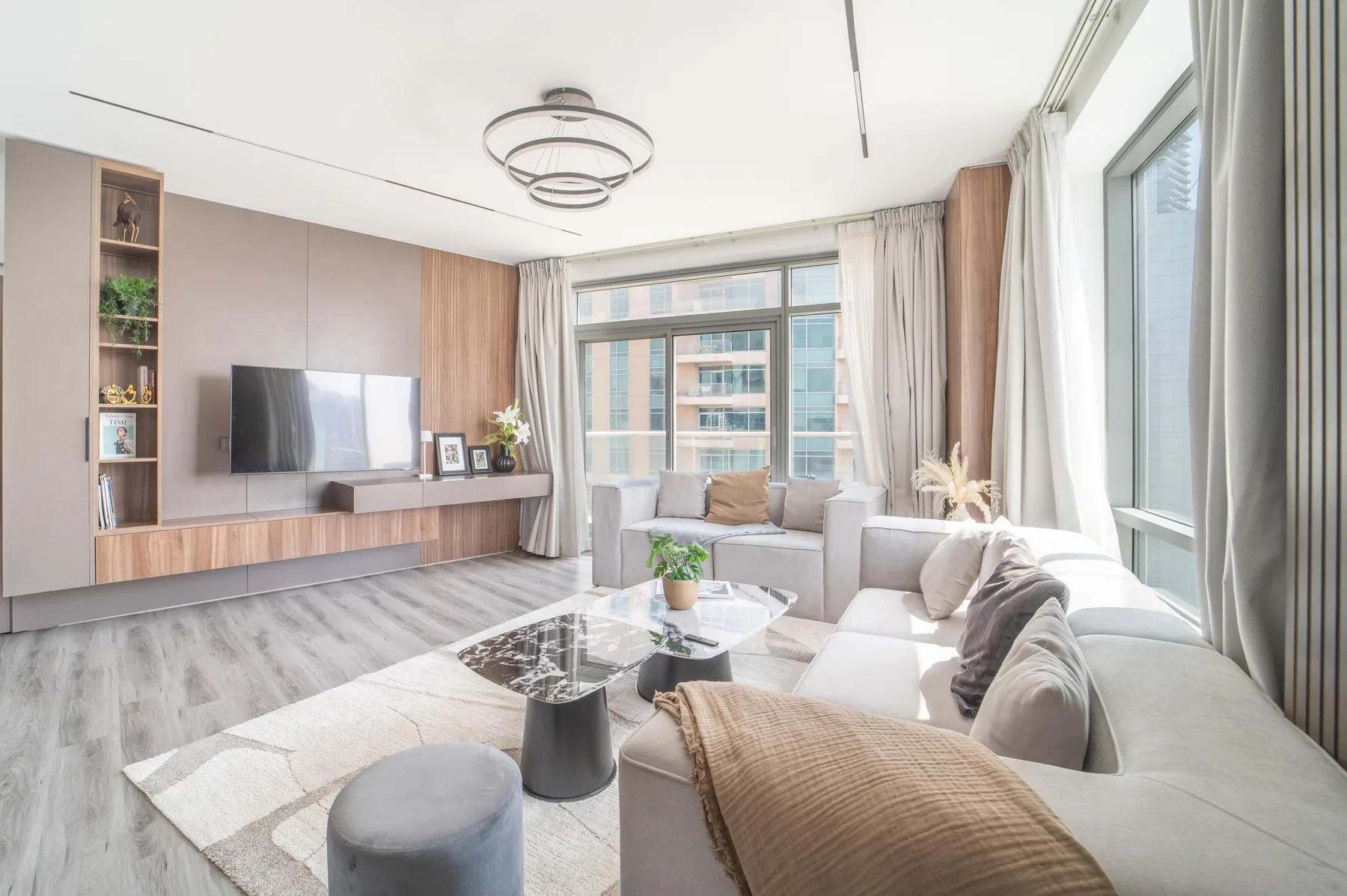 Una sala luminosa con asientos alrededor de una mesa de centro y grandes ventanas.
