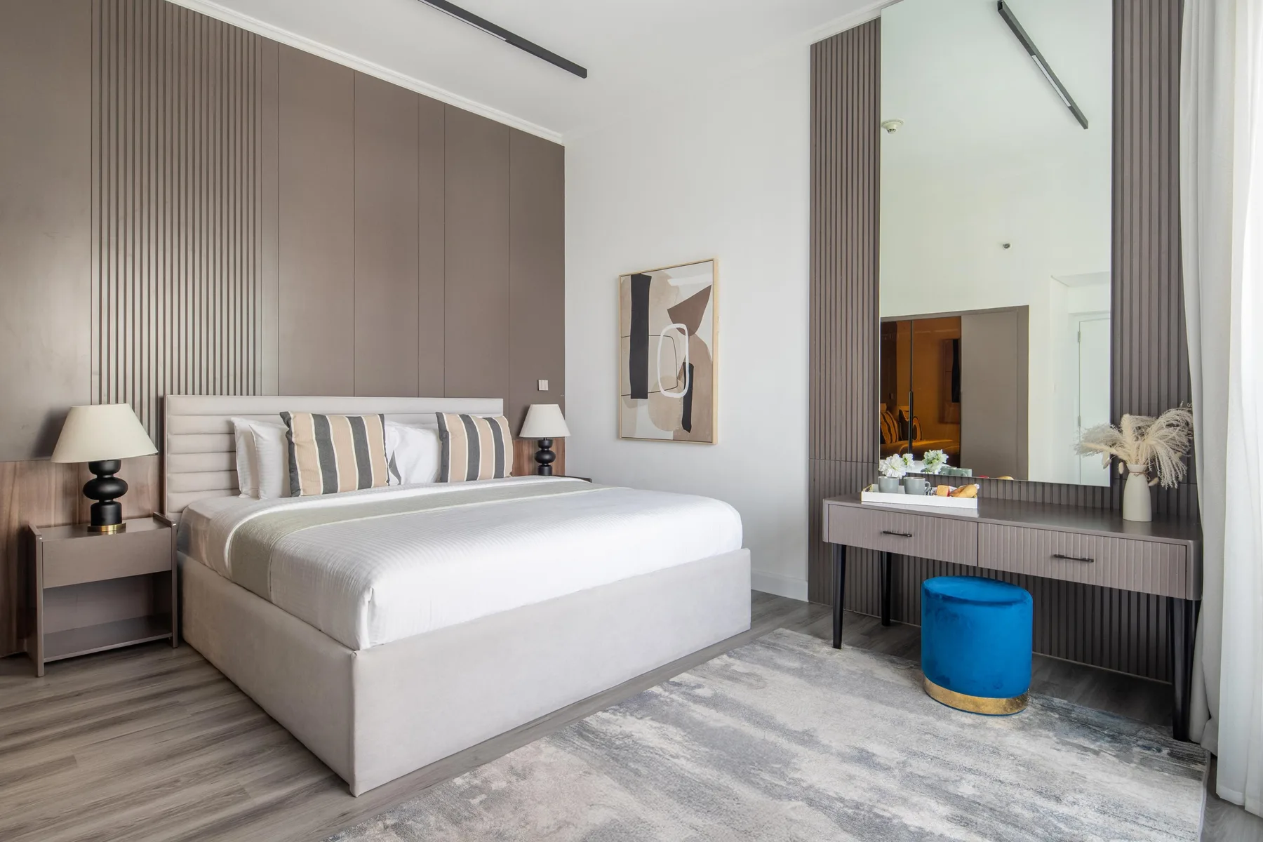 Un dormitorio con una cama grande, mesitas de noche y un espejo de pared.