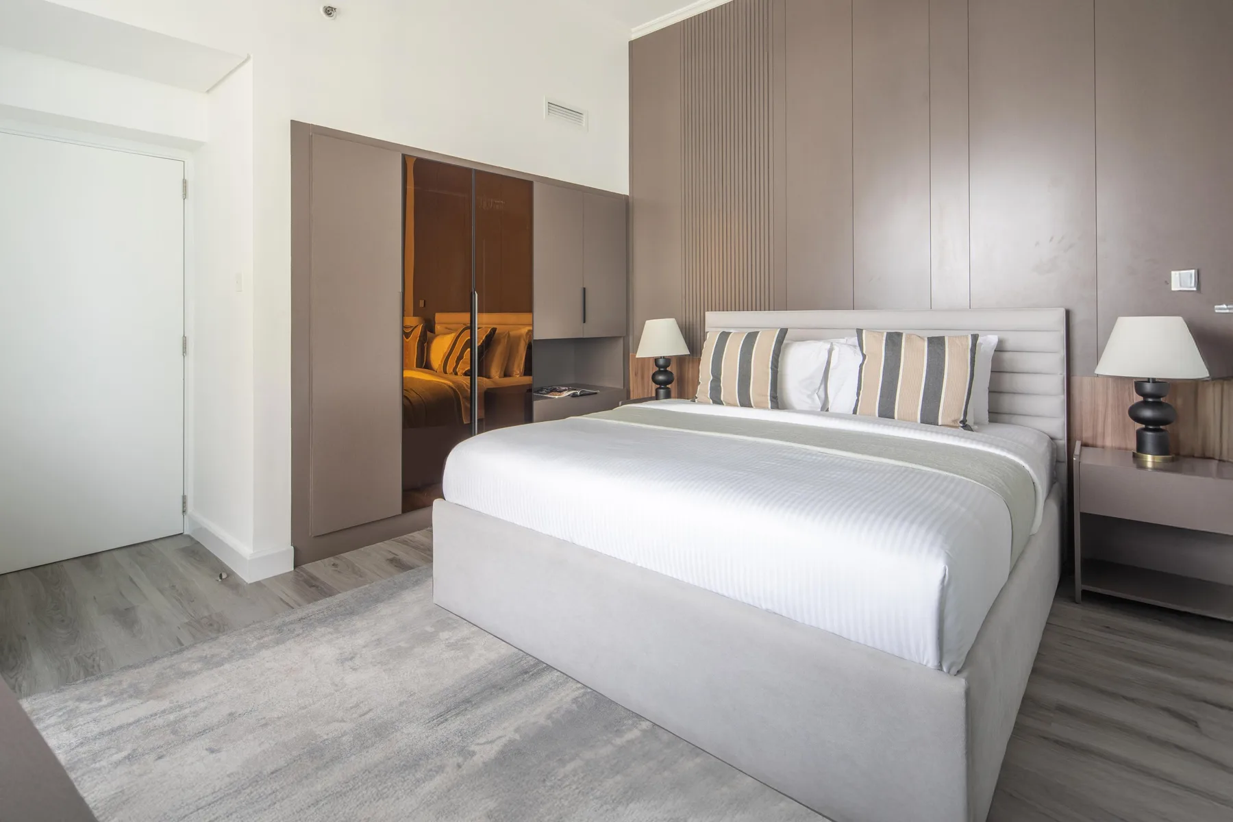 Un dormitorio con una cama grande, almohadas a rayas y lámparas de noche.