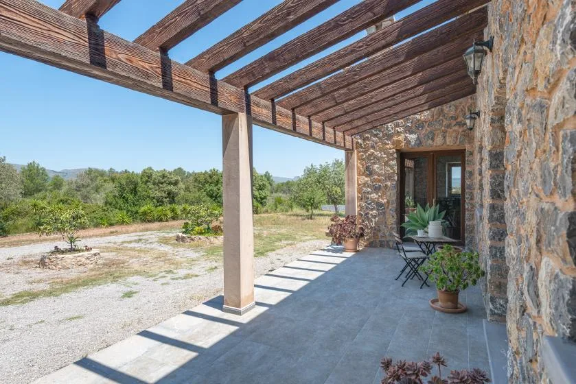 A covered outdoor patio with stone walls, seating, and a view of the surrounding landscape.