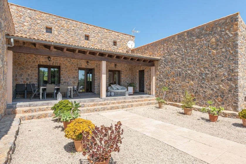 A stone courtyard with a covered patio, outdoor seating, and potted plants.