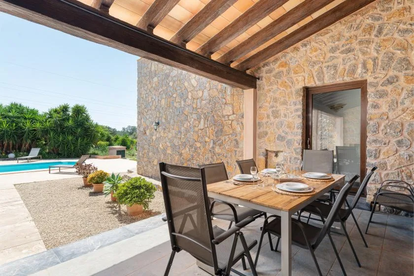 A covered outdoor dining area with a table and seating beside a swimming pool.