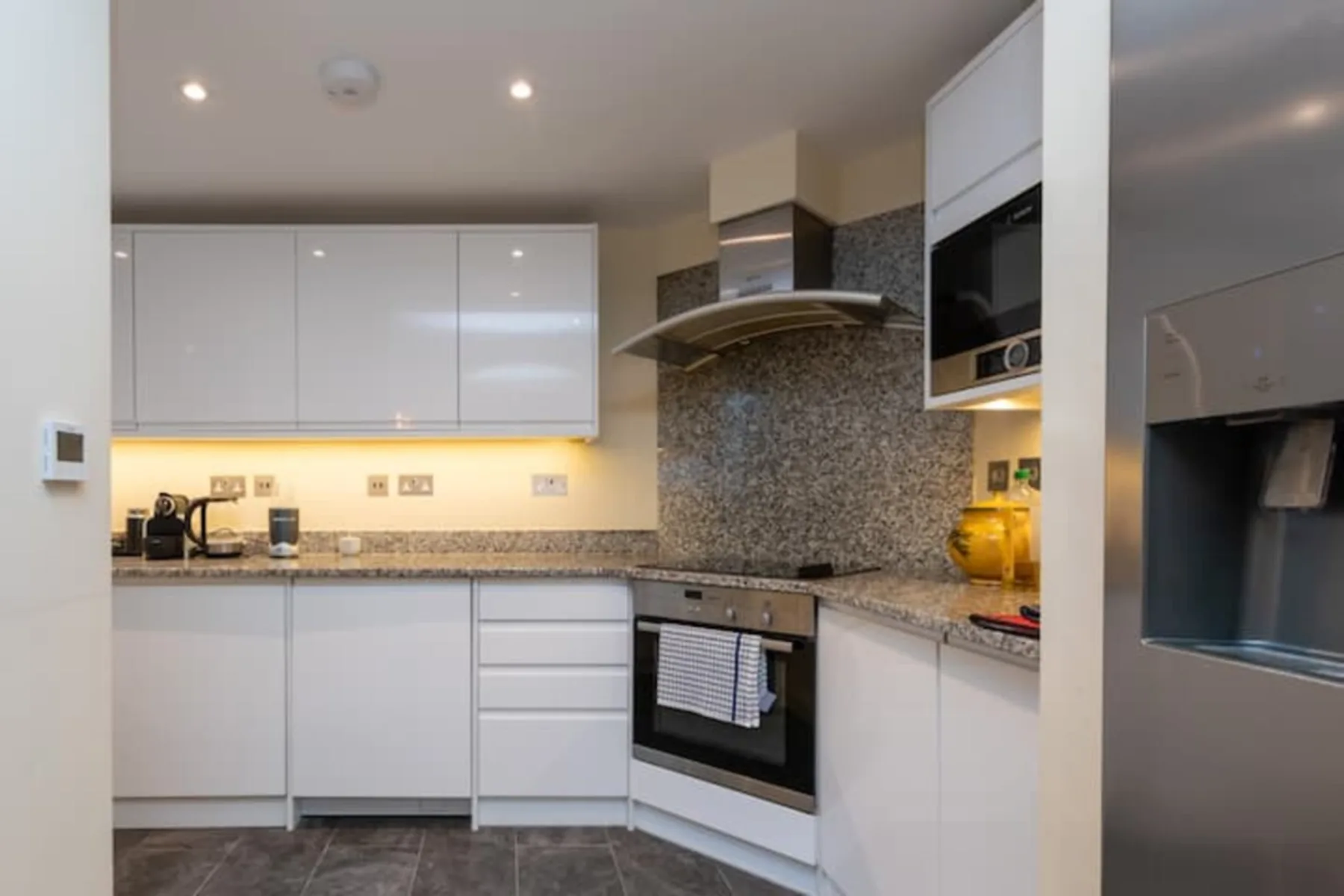 Una cocina moderna con gabinetes blancos y un horno empotrado.