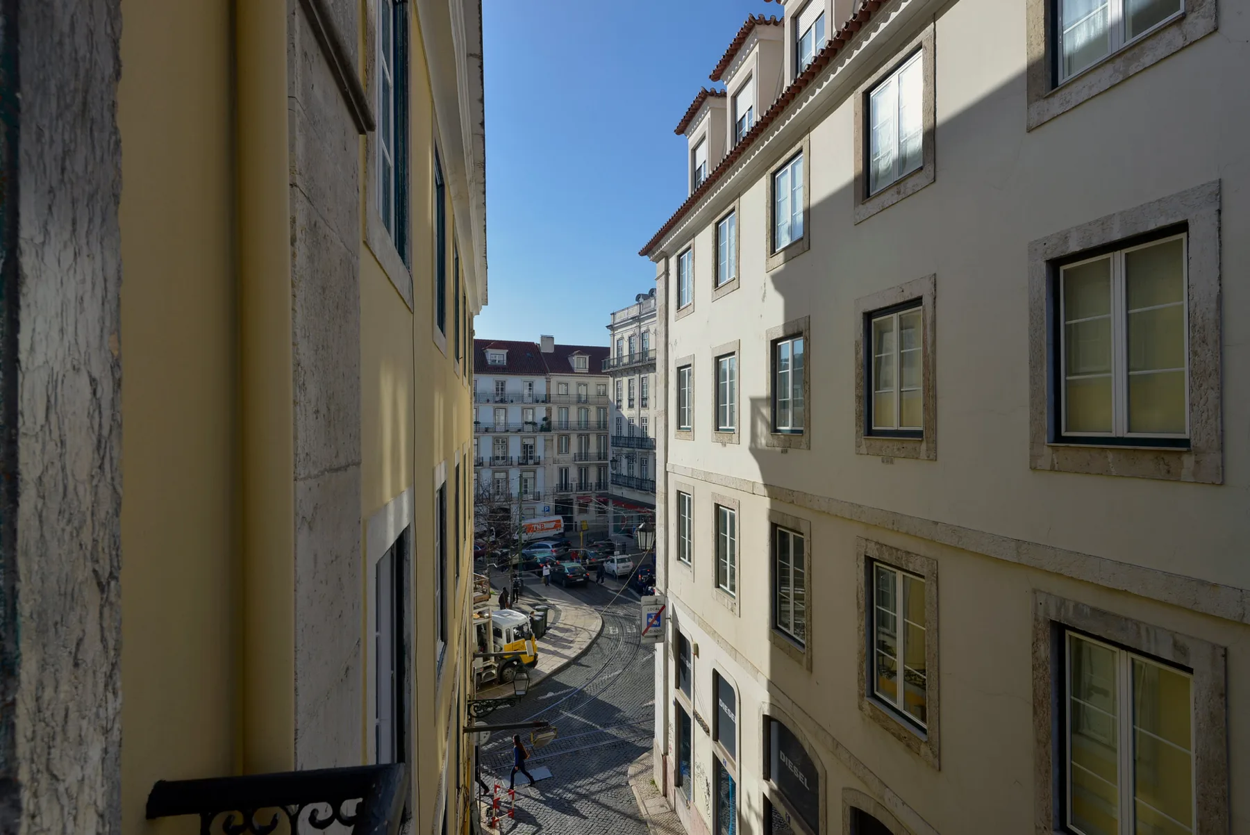 Se ve una calle estrecha entre edificios cercanos bajo un cielo despejado.