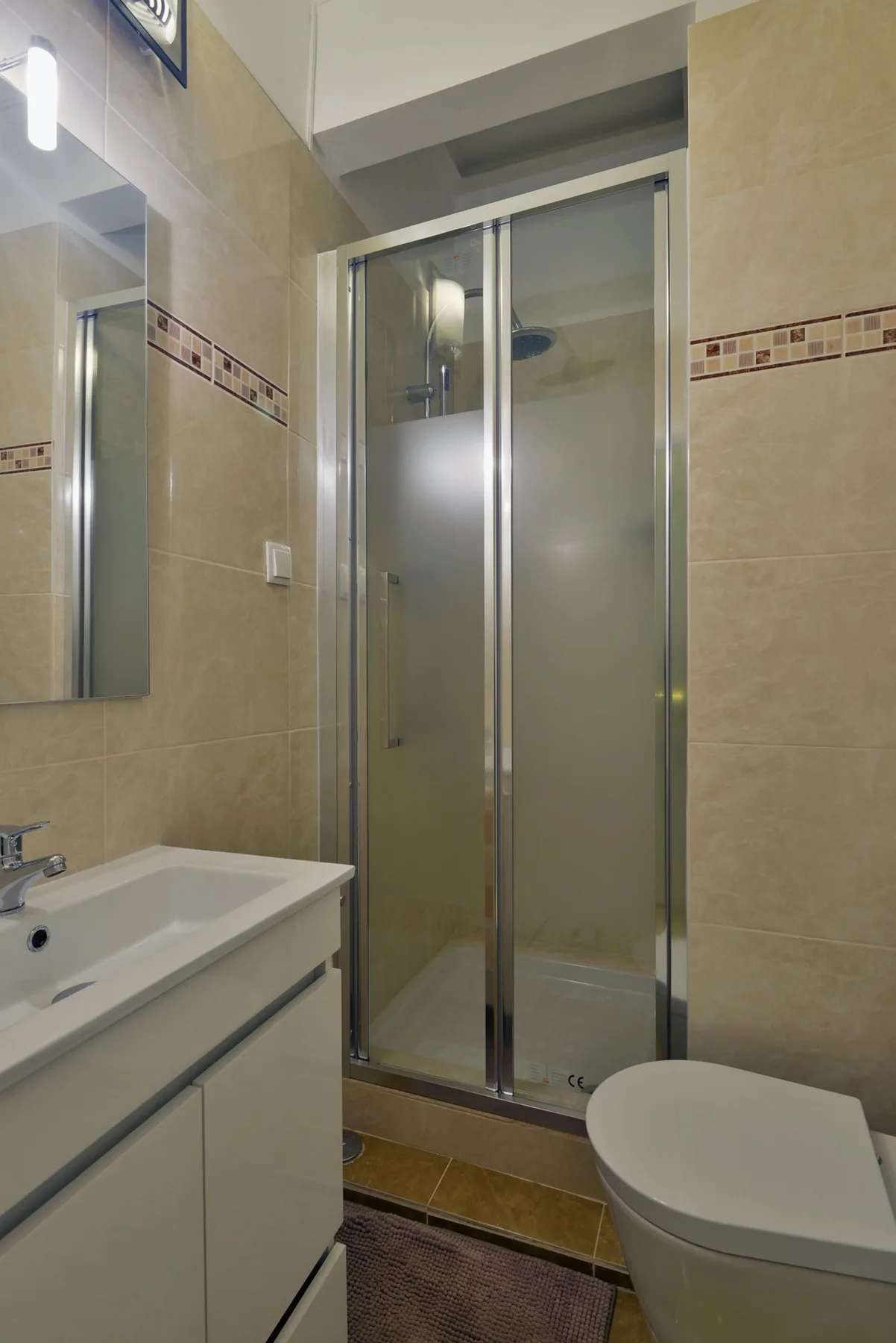 Un baño con azulejos, lavabo, inodoro y ducha de cristal.