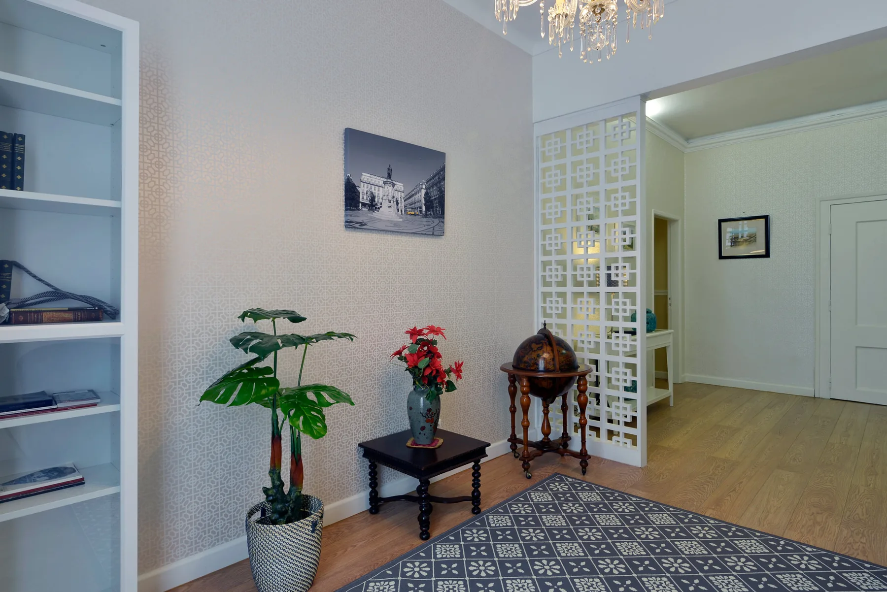 Una sala de estar con una alfombra estampada, plantas y una mesita.