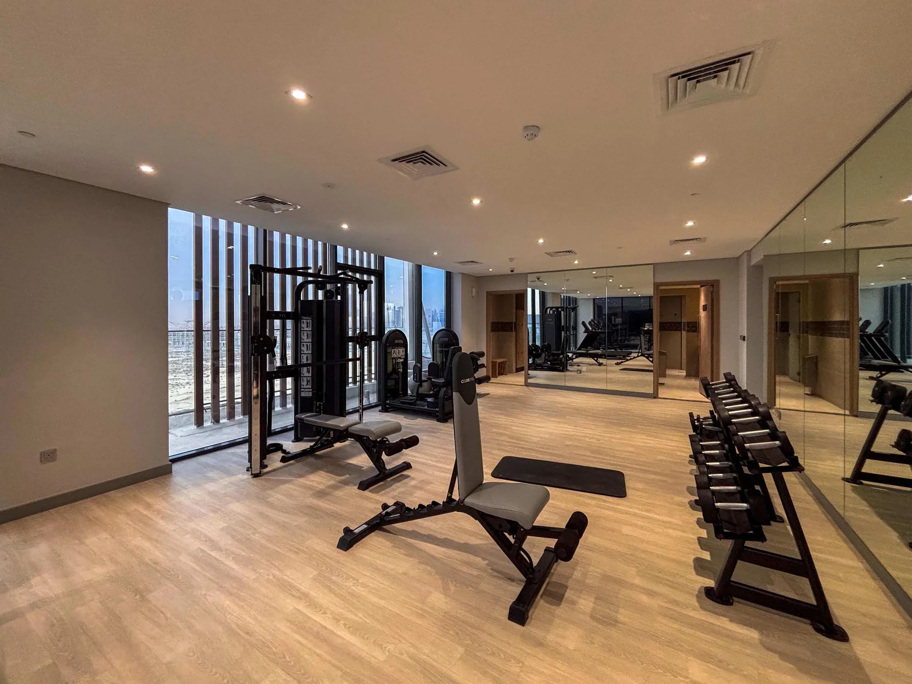 Un gimnasio con equipos de ejercicio, pesas y paredes con espejos.