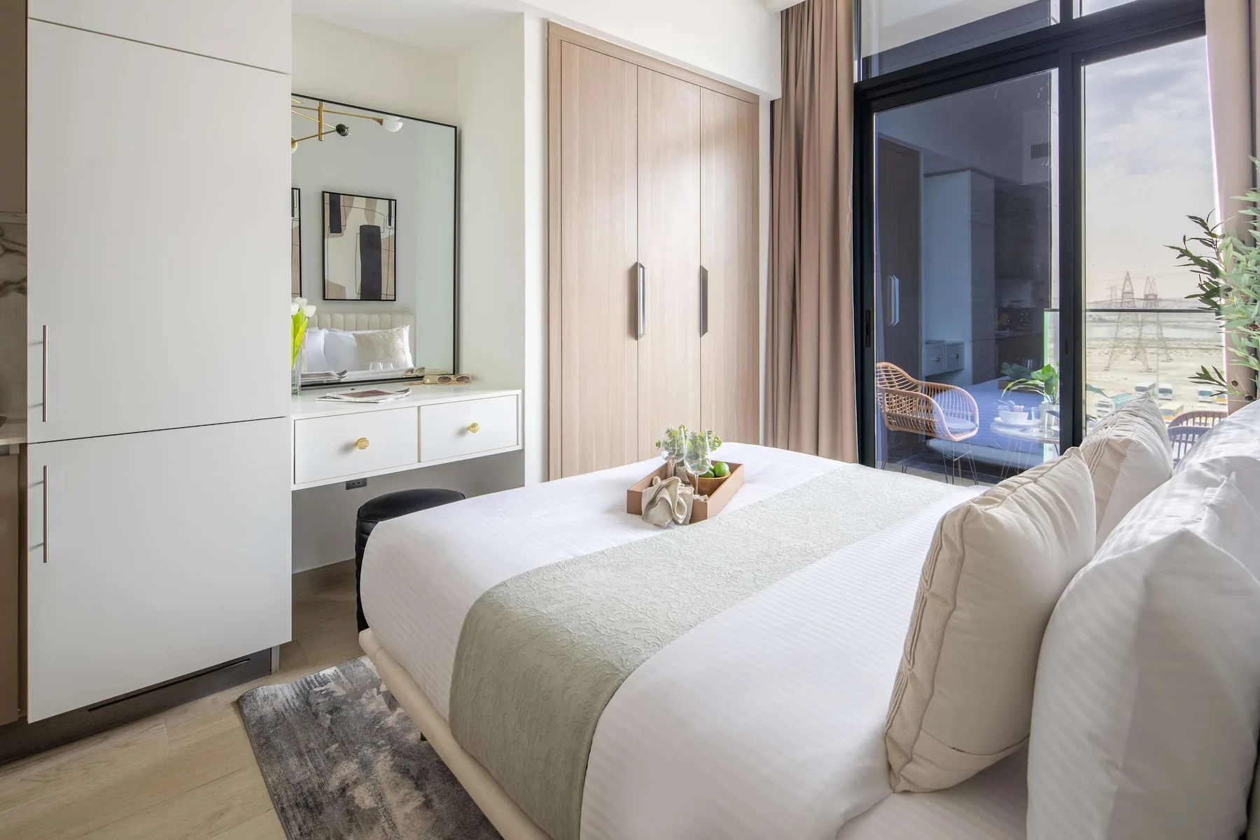 Un dormitorio luminoso con una cama bien tendida y una ventana grande.