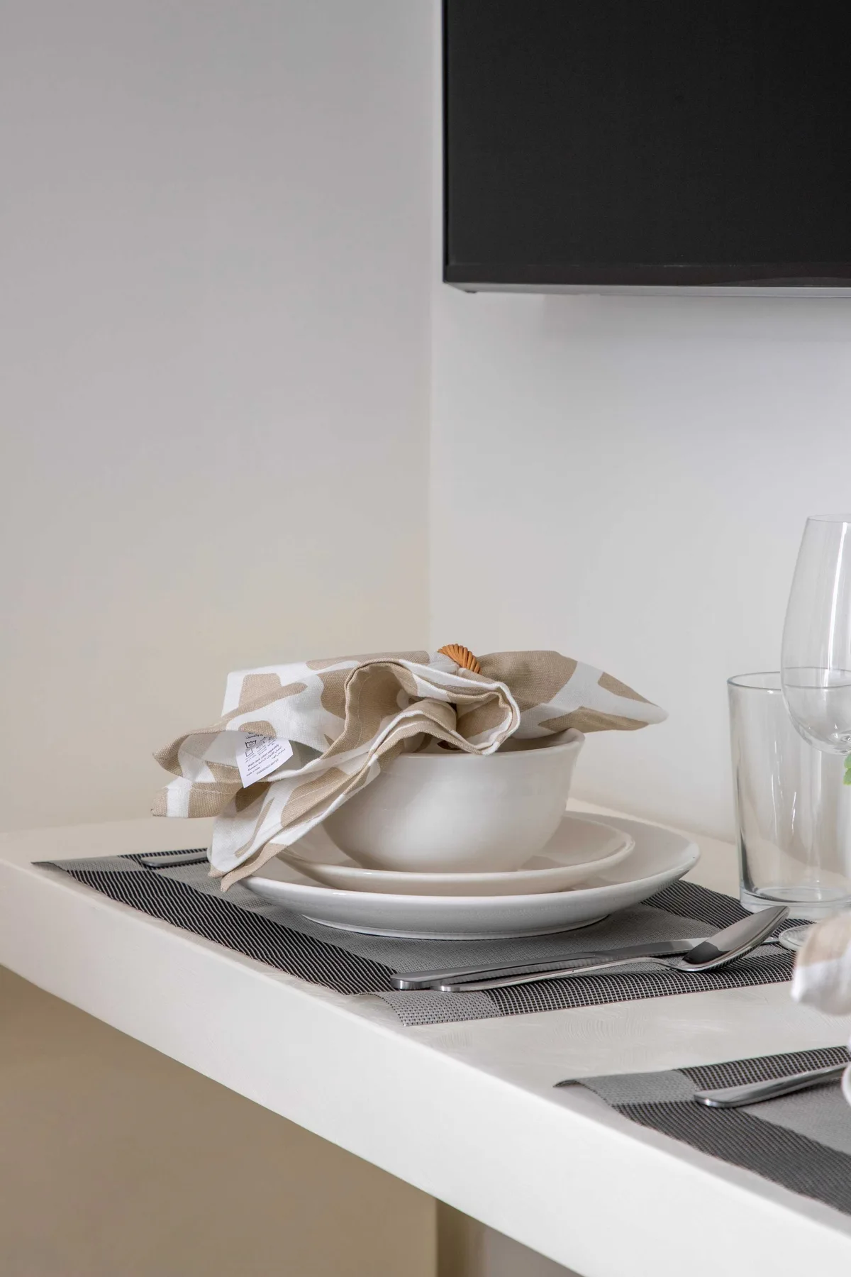 Una mesa de comedor está puesta con platos, servilletas dobladas y cristalería.
