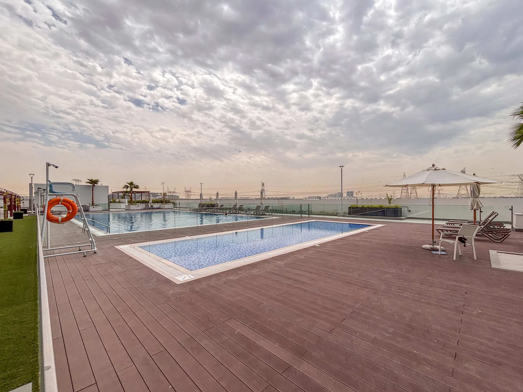 Una terraza con piscina al aire libre, asientos de descanso y un cielo ampliamente nublado.