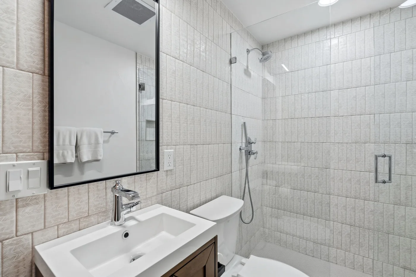 A tiled bathroom with a sink, toilet, and glass shower.