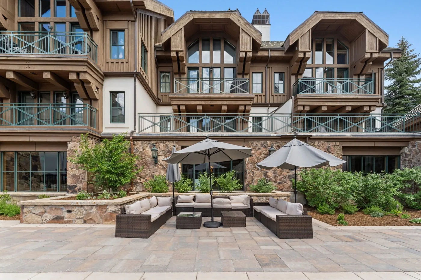 A multi-story building overlooks a paved patio with outdoor seating and umbrellas.