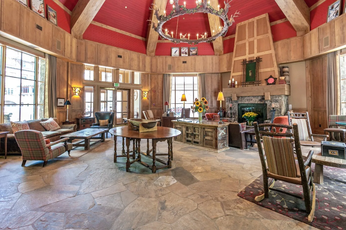 A spacious living room with seating, a fireplace, and a high red ceiling.