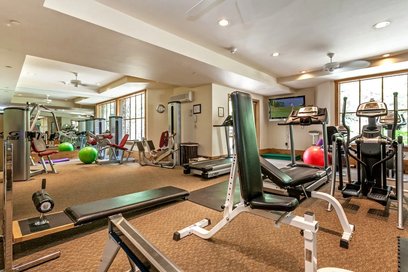 A gym with exercise equipment and large windows.