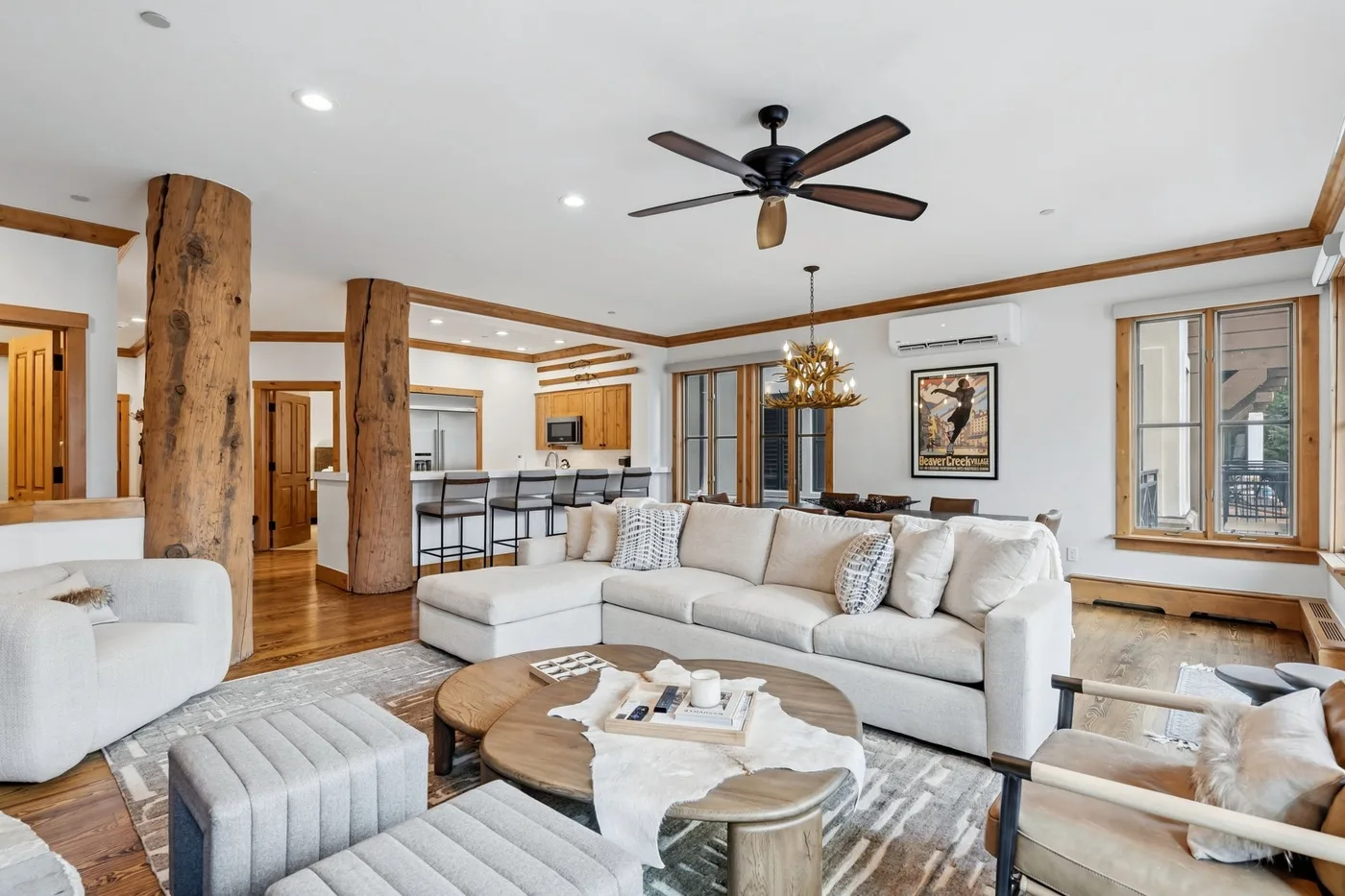 A bright living room with sectional seating and an open kitchen behind it.