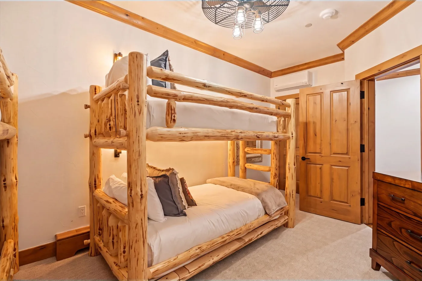A bedroom with a wooden bunk bed and light-colored bedding.