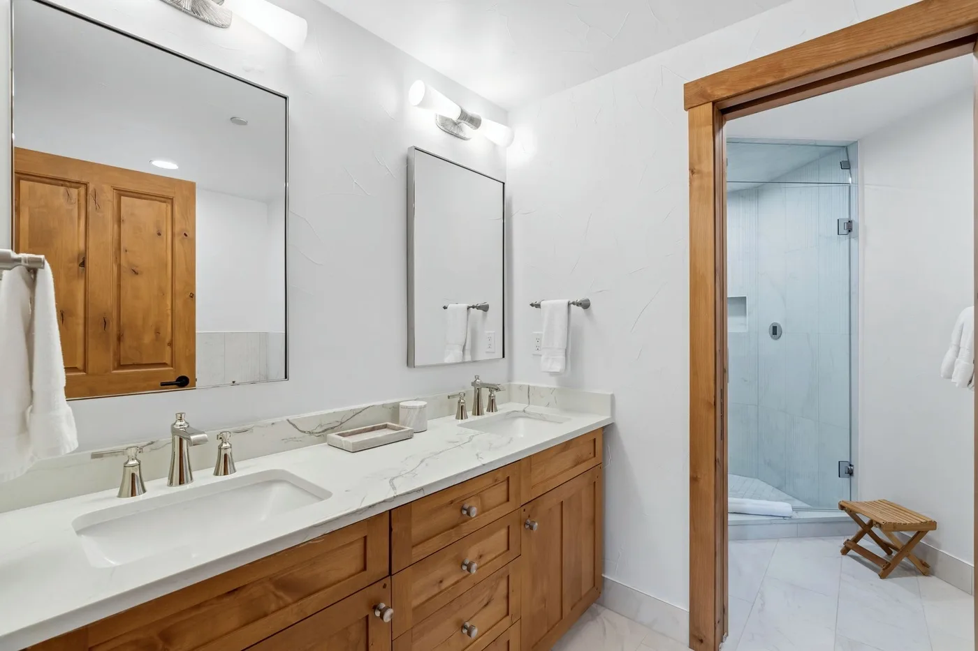 A bright bathroom with a long vanity and a glass-enclosed shower.