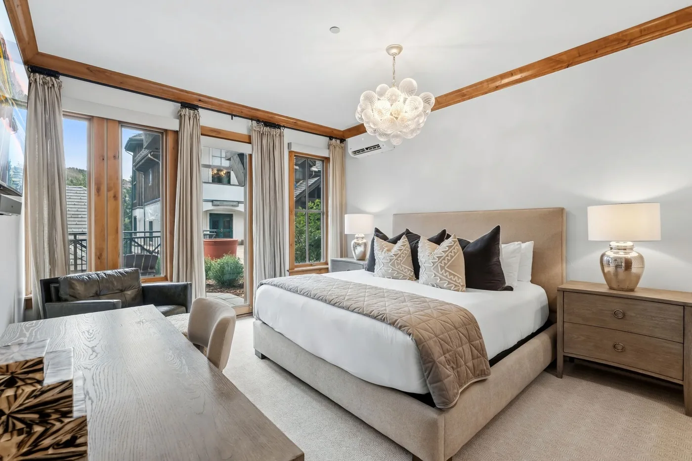 A bedroom with a large bed, bedside table, and tall windows.