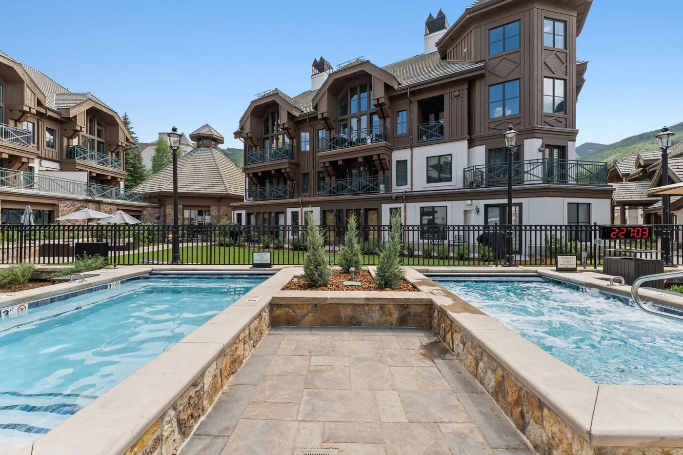 An outdoor pool sits in front of a multi-story building with balconies.