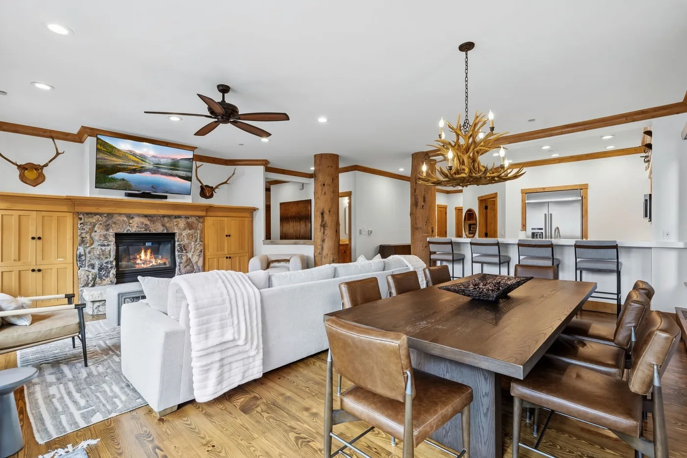 An open living and dining area features a stone fireplace and a large wooden table.