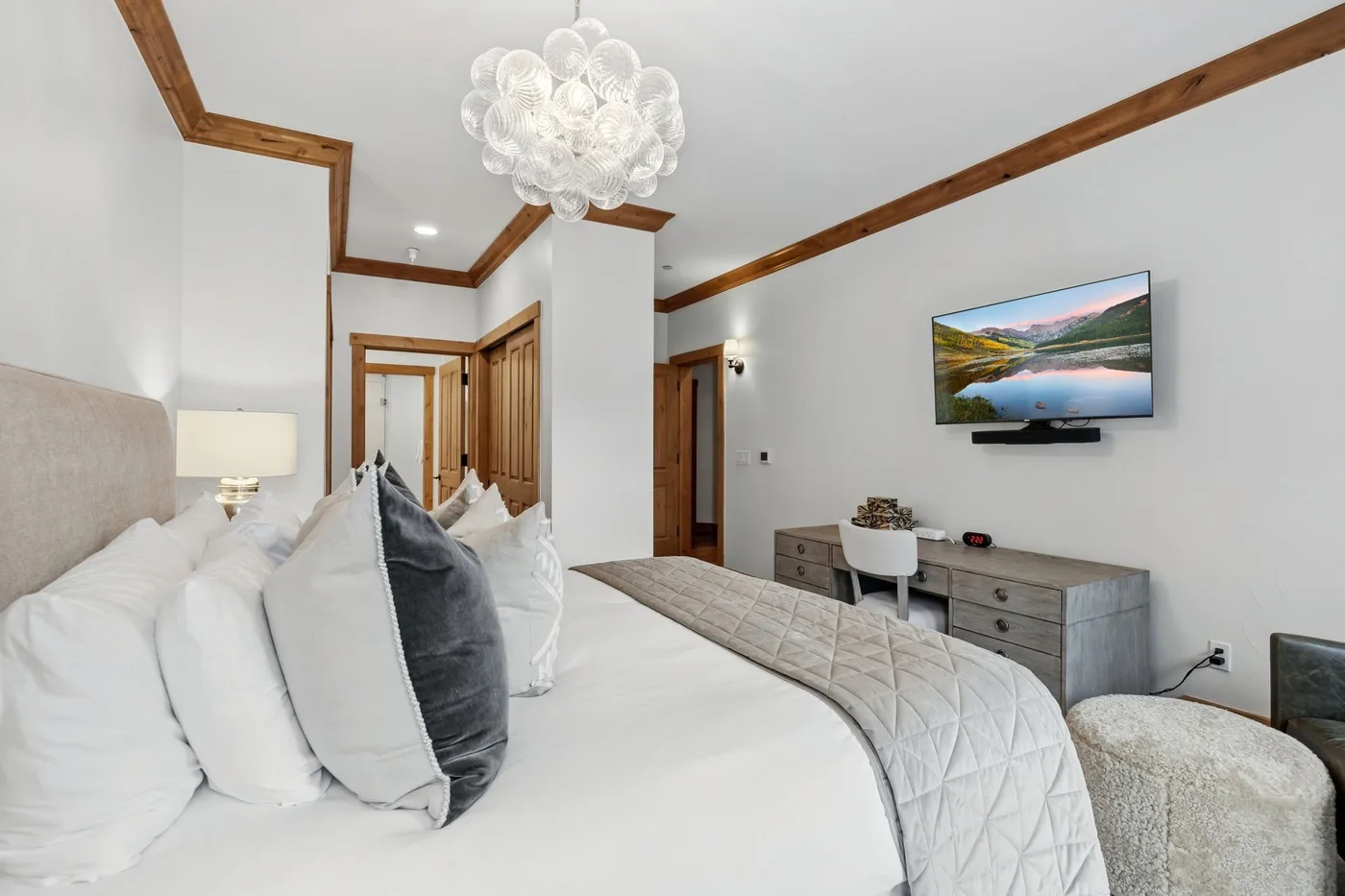 A bedroom with a bed, wall-mounted television, and dresser.