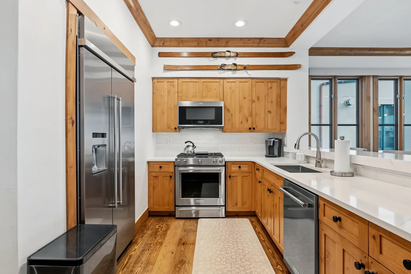 A bright kitchen with wooden cabinets, stainless steel appliances, and a long white island.