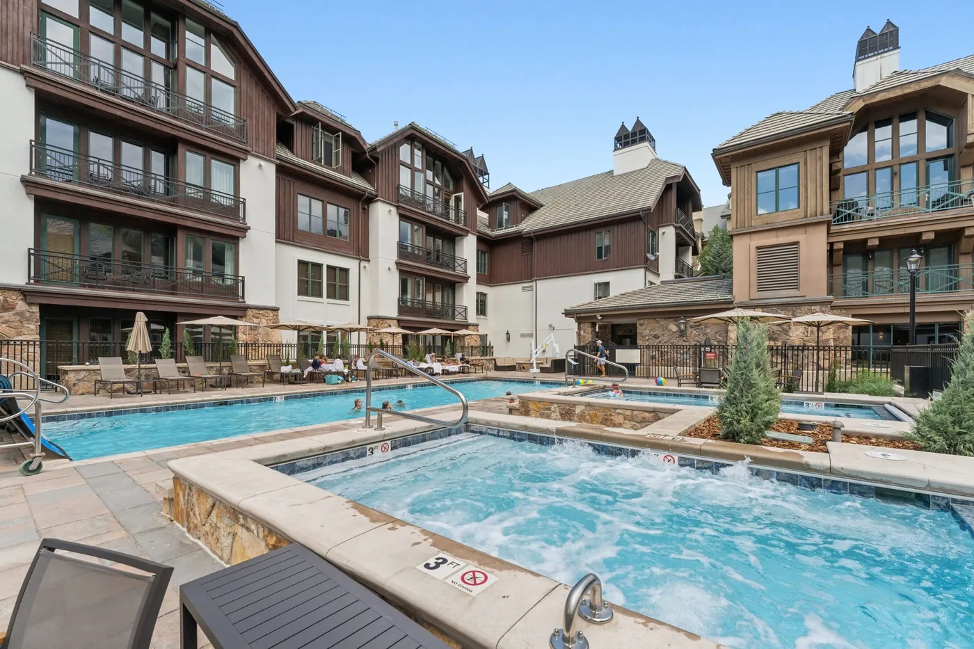 An outdoor pool courtyard sits among multi-story buildings with balconies.