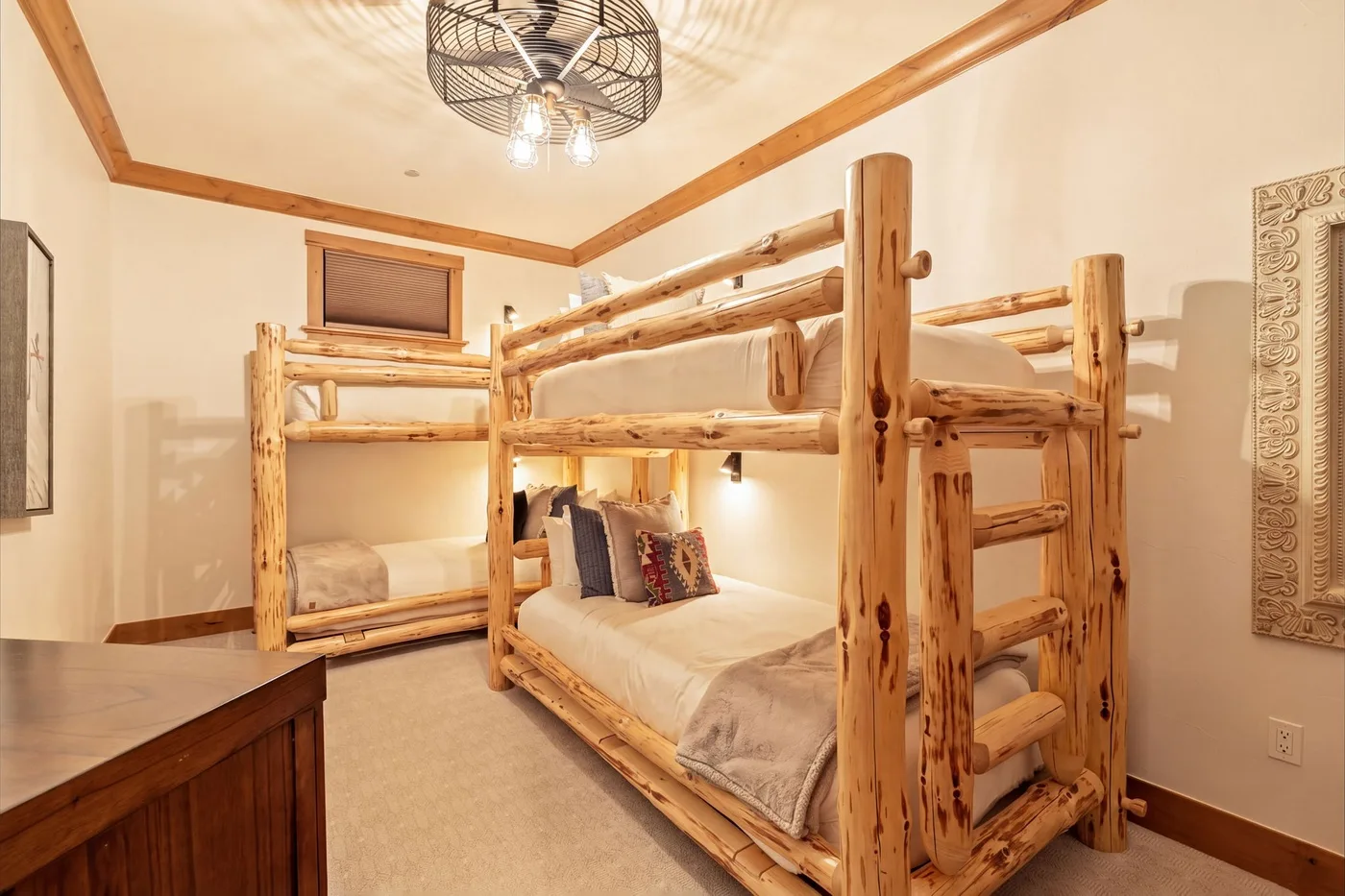 A bedroom with a rustic wooden bunk bed and a ceiling fan.