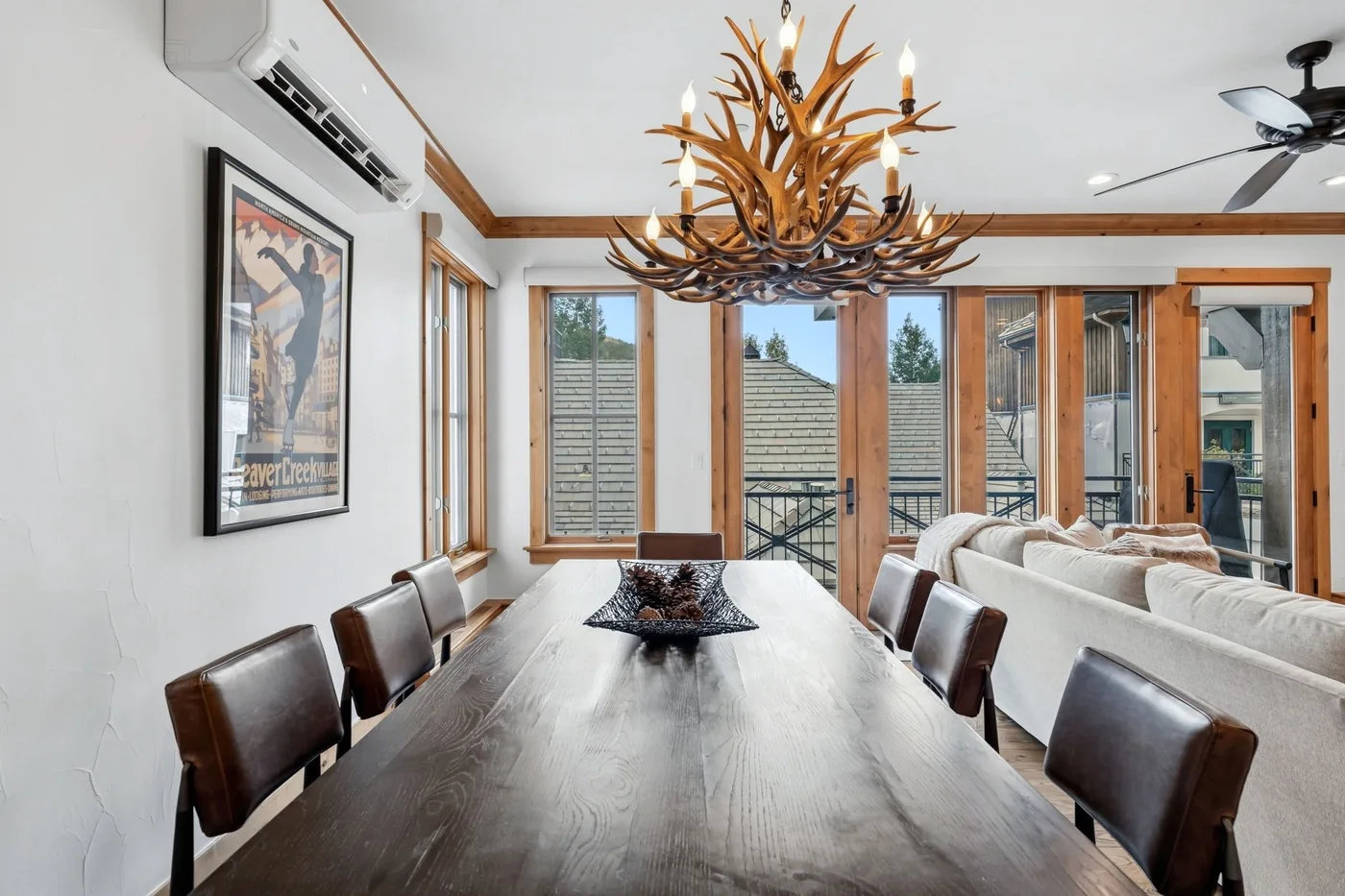 Dining area with a long table beside windows and a living room seating area.
