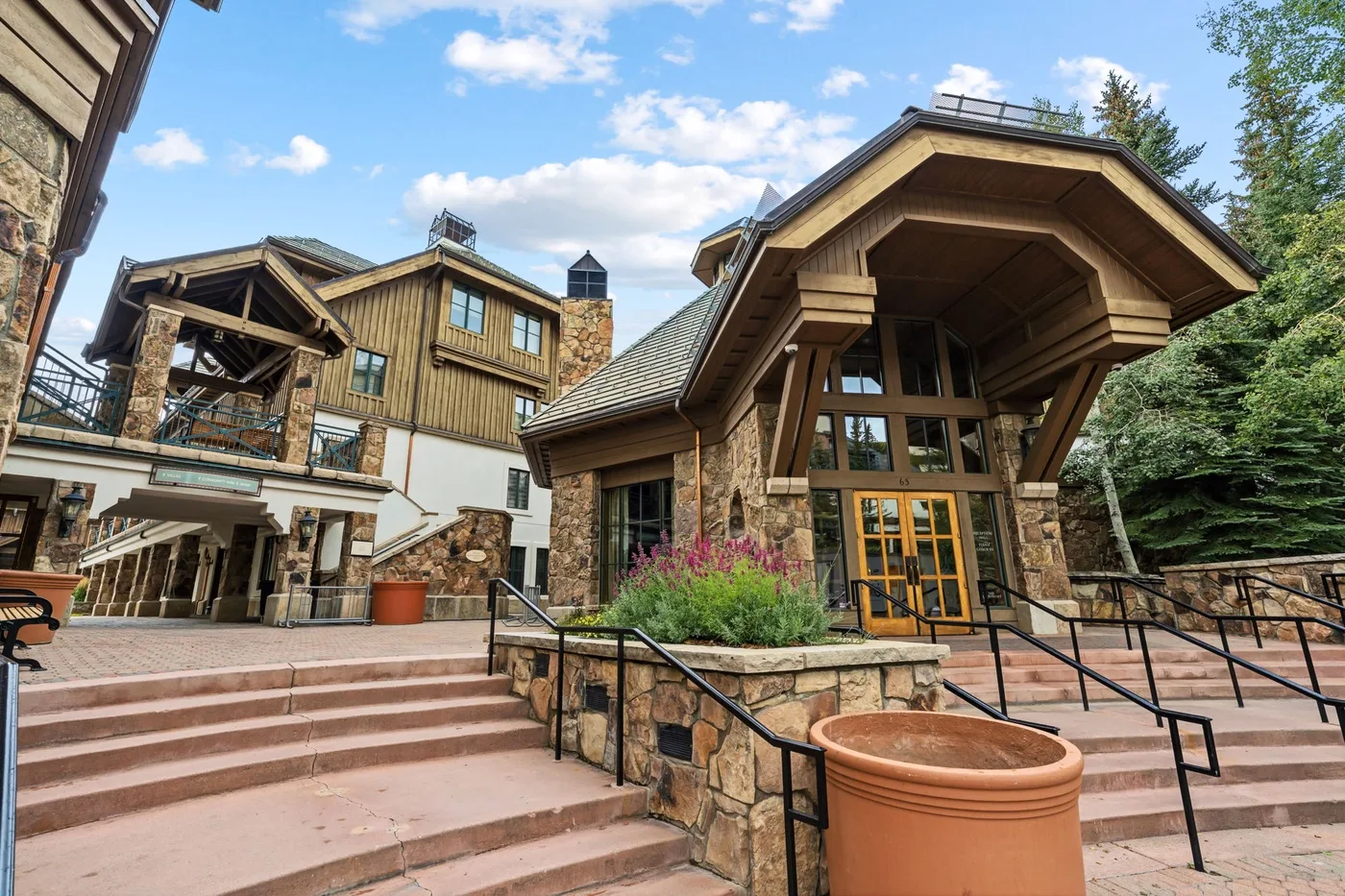 A lodge-style building with stone walls, timber details, and broad outdoor steps.