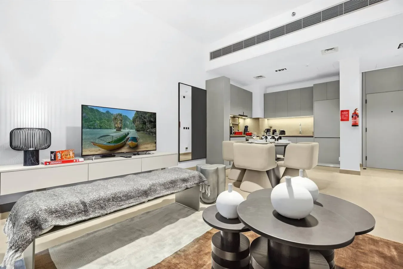 A modern living area with a television, dining table, and open kitchen.
