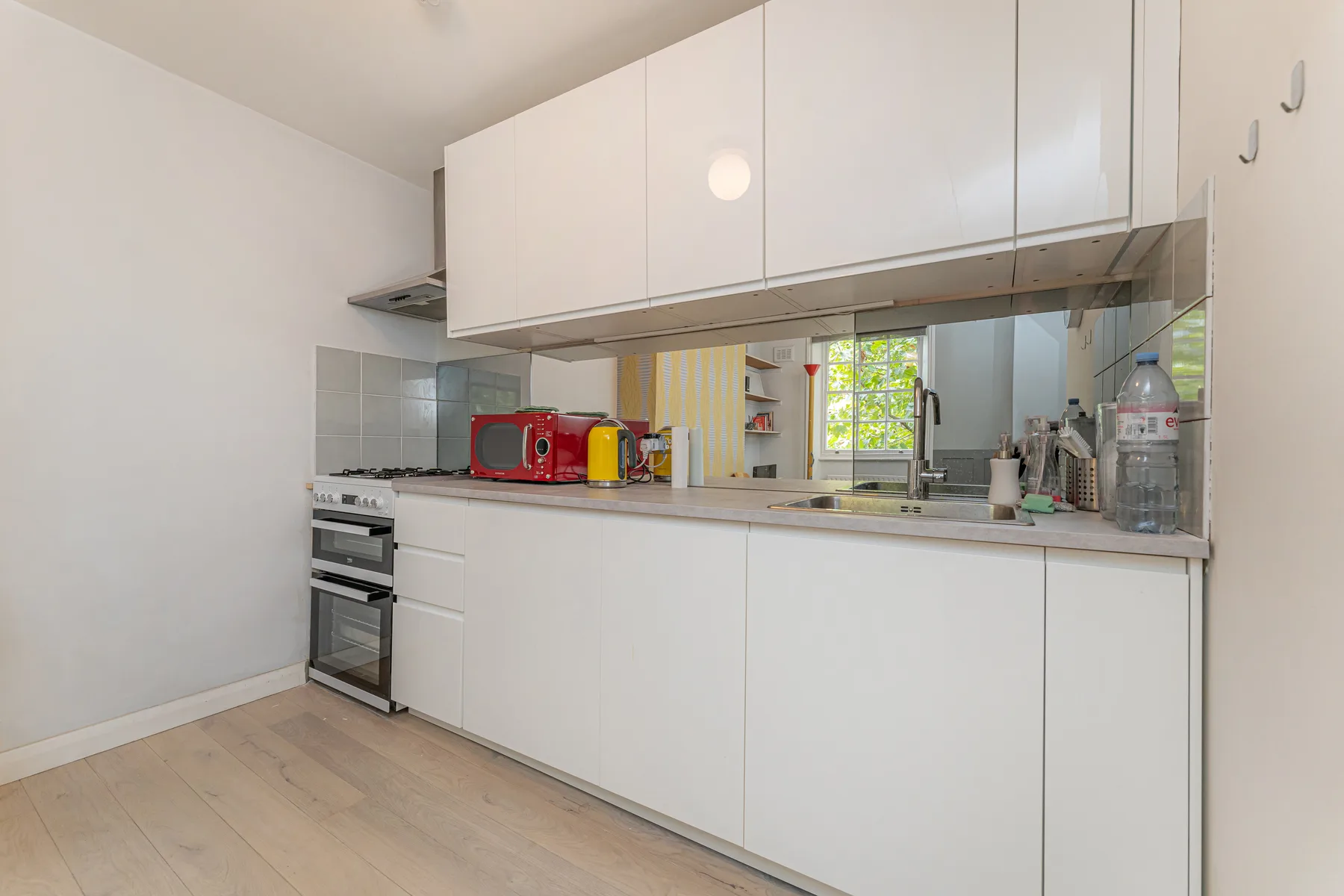 Una cocina luminosa con gabinetes blancos, una encimera y una ventana.